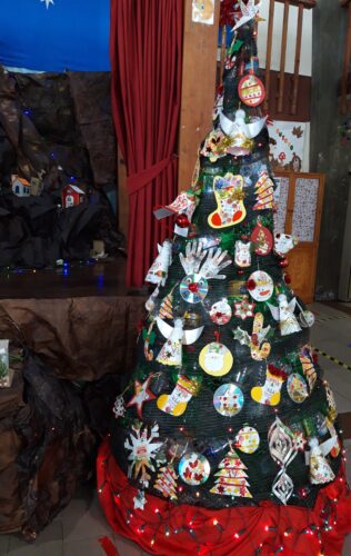 Árvore de Natal Ecológica<br/>A árvore de Natal ficou muito colorida e bastante bonita com os trabalhos reutilizados feitos pelas crianças.