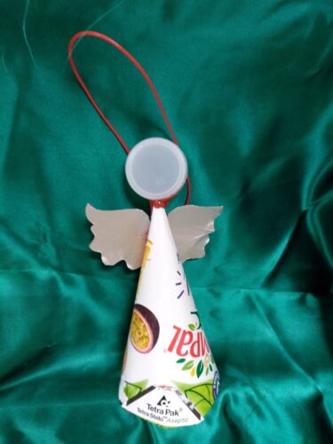 Usamos um pacote da compal, as asas foram feitas no mesmo material e para a cabeça tivemos a ideia de colocar uma tampa de iogurte branca. Este anjo simboliza a ingenuidade e alegria das crianças.