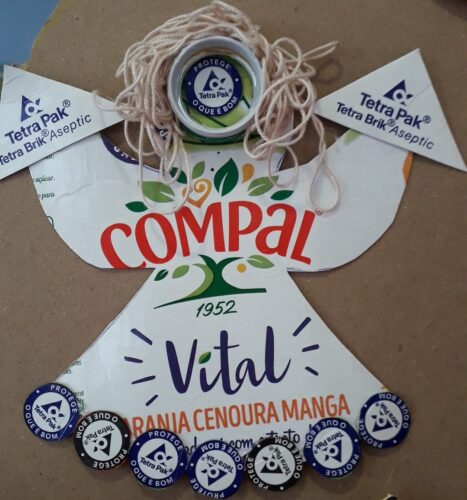 Anjo elaborado por alunas do 5º E, utilizando embalagens Tetra Pack da Compal, símbolos solicitados e fio grosso para representar os cabelos.