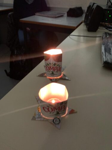 Dois porta-velas, com velas acesas, colocados na secretária do professor.