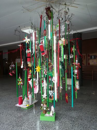 Árvore de Natal suspensa (construída com tubos elétricos pintados e ramos de um arbusto da escola) ornamentada com todos os enfeites dos alunos